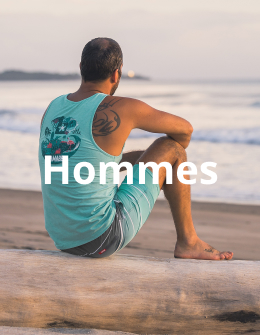 Homme assis sur la plage, vêtu d’un débardeur bleu et d’un boardshort assorti de la marque Hamabe, profitant d’un moment de détente au bord de la mer.